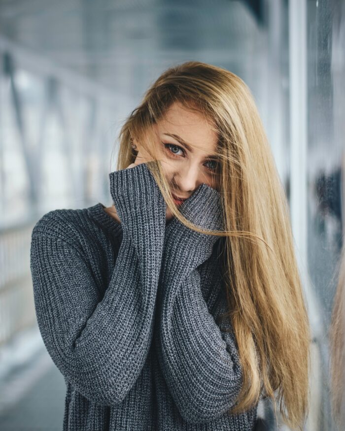 woman in gray knitted sweater with hands on cheeks