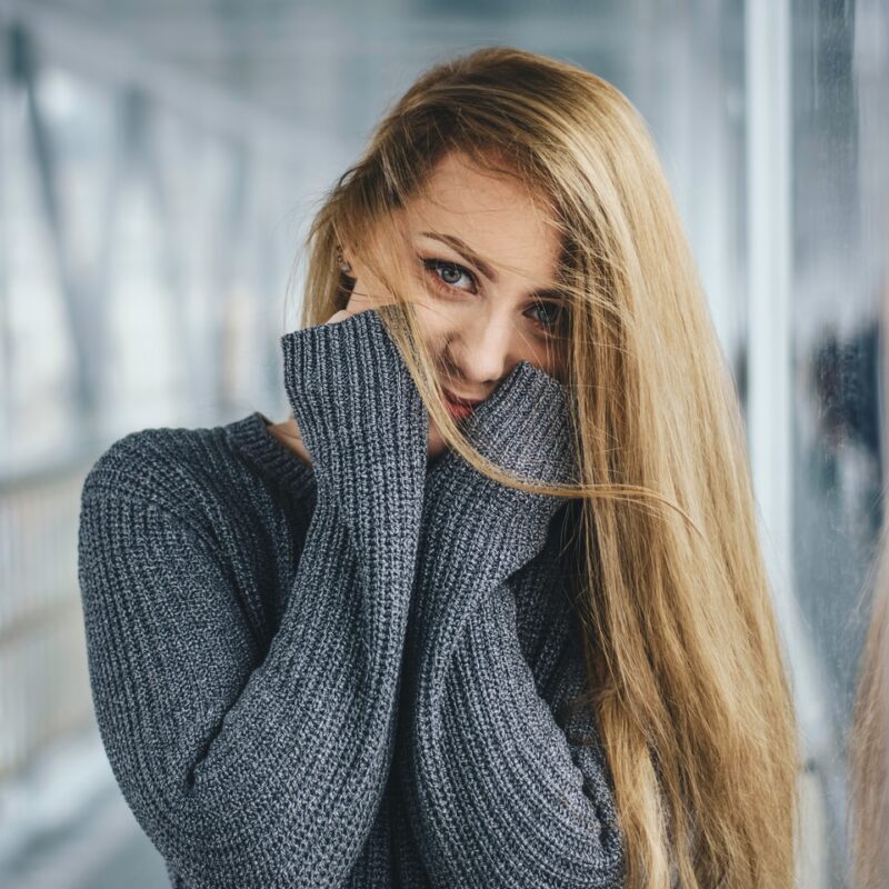 woman in gray knitted sweater with hands on cheeks